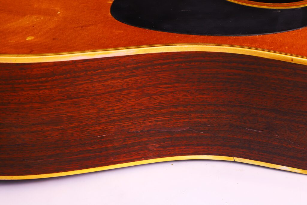 Nahaufnahme Der Seite Einer Martin D-28 1971 Akustik Gitarre, Die Die Holzmaserung Und Die Gelbe Verzierung Hervorhebt, Wobei Im Oberen Bereich Ein Teil Der Decke Der Gitarre Zu Sehen Ist.