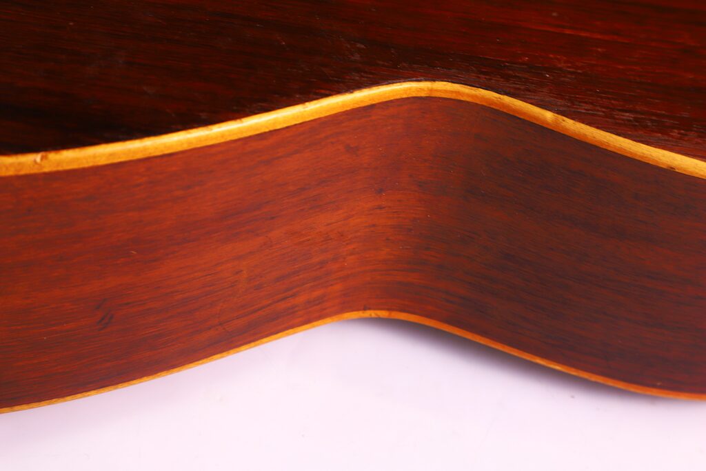 Primo piano del lato legno della chitarra classica Salvador Ibanez 1900, che evidenzia la forma curva, la superficie liscia e il contrasto tra le venature chiare e scure del legno.