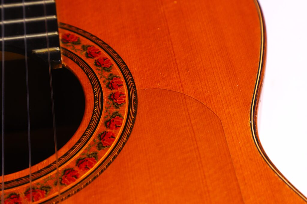 Nahaufnahme Des Korpus Der Lester Devoe 1996 Negra Flamenco Gitarre. Hervorzuheben Sind Das Schallloch, Die Saiten Und Die Blumengemusterte Rosette. Feine Holzmaserung Und Detaillierte Handwerkskunst Sind Deutlich Sichtbar.