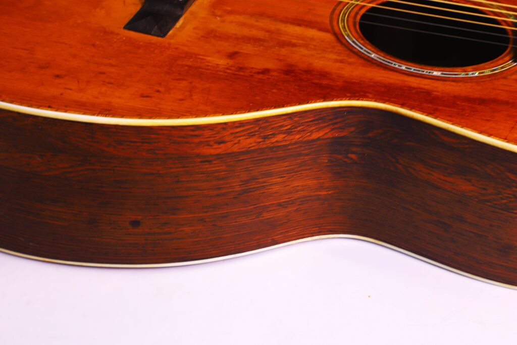 Nahaufnahme Der Seite Und Der Decke Einer Martin 0-30 1917 Akustik-Gitarre Mit Rötlich-Brauner Holzmaserung Und Cremefarbenem Einband, Dargestellt Vor Weißem Hintergrund.