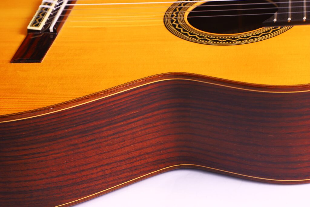 Nahaufnahme Der José Ramírez Rb-A 636 Klassische Gitarre. Hervorzuheben Sind Die Glatte, Gewellte Holzseite Und Der Untere Korpus. Die Gitarre Verfügt Über Eine Warme Holzoberfläche, Feine Maserungen Und Dekorative Schalllochdetails.