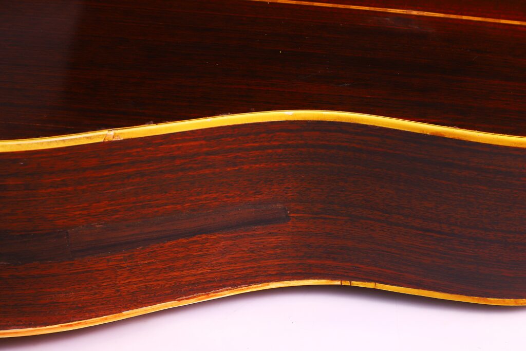 Nahaufnahme Der Seite Einer Martin D-28 1971 Akustik-Gitarre Mit Dunkler Holzmaserung, Glänzender Oberfläche Und Gelblichem Binding Entlang Der Gewölbten Kante.