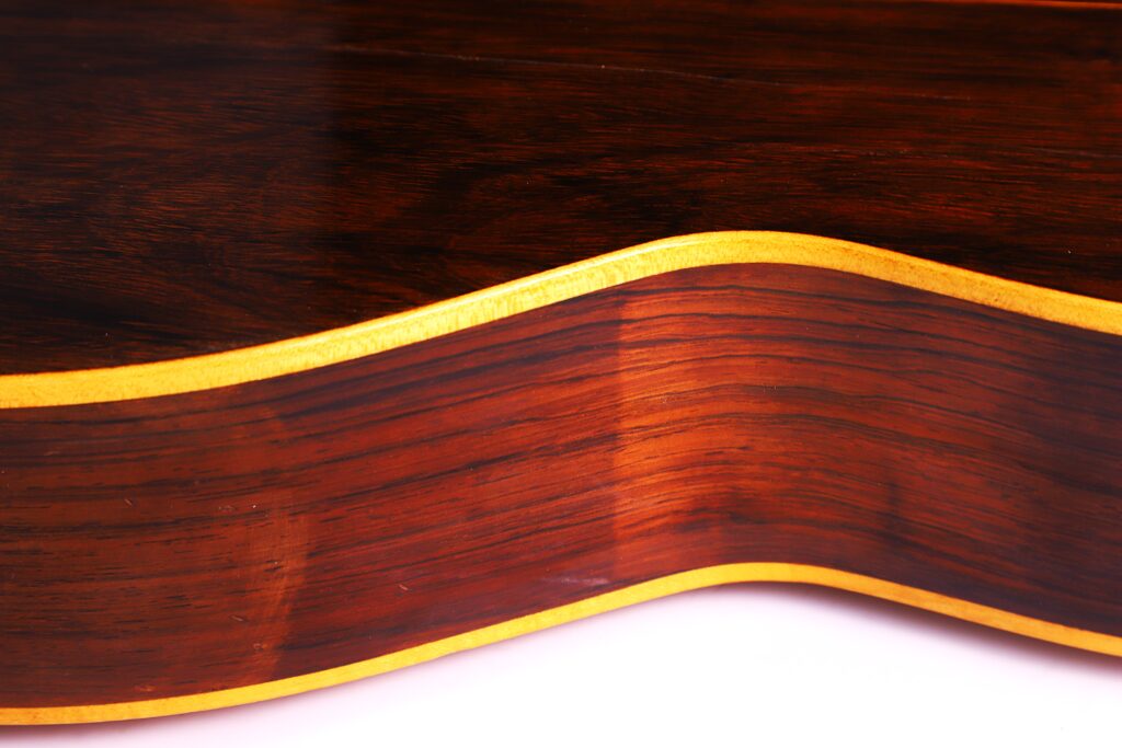 Nahaufnahme Der Seite Der Julián Gómez Ramírez 1933 Klassische Gitarre, Die Die Glänzende Dunkelbraune Holzmaserung Und Die Gelbliche Verzierung Entlang Der Kante Hervorhebt.