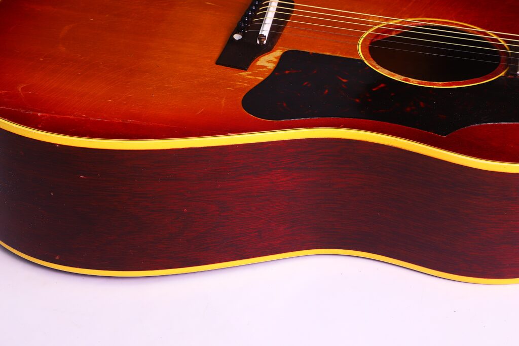 Nahaufnahme Der Seite Und Des Unteren Korpus Einer Gibson J-45 1962 Akustik Gitarre Mit Rötlich-Brauner Lackierung, Gelbem Binding Und Einem Teil Des Schalllochs Und Schlagbretts.