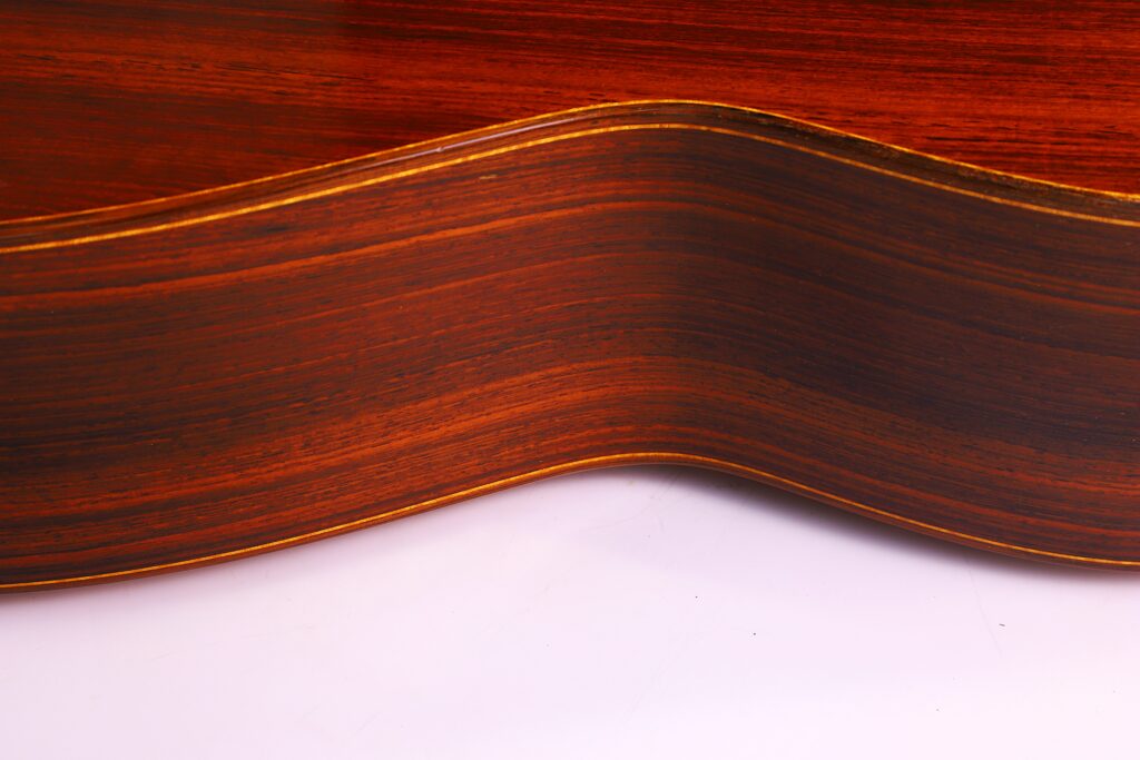 Nahaufnahme Der Seite Der Lester Devoe 1996 Negra Flamenco Gitarre, Die Die Reiche, Dunkle Holzmaserung Und Die Glatte, Gewellte Kontur Vor Einem Weißen Hintergrund Hervorhebt.