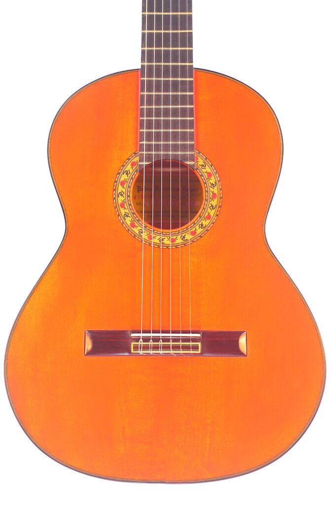 Die Pedro Fernández Luque 2020 Blanca Flamenco Gitarre Ist Eine Klassische Akustikgitarre Mit Einem Holzkorpus, Sechs Saiten, Einer Dekorativen Rosette Und Einer Glänzenden, Orange-Braunen Lackierung Auf Weißem Hintergrund.