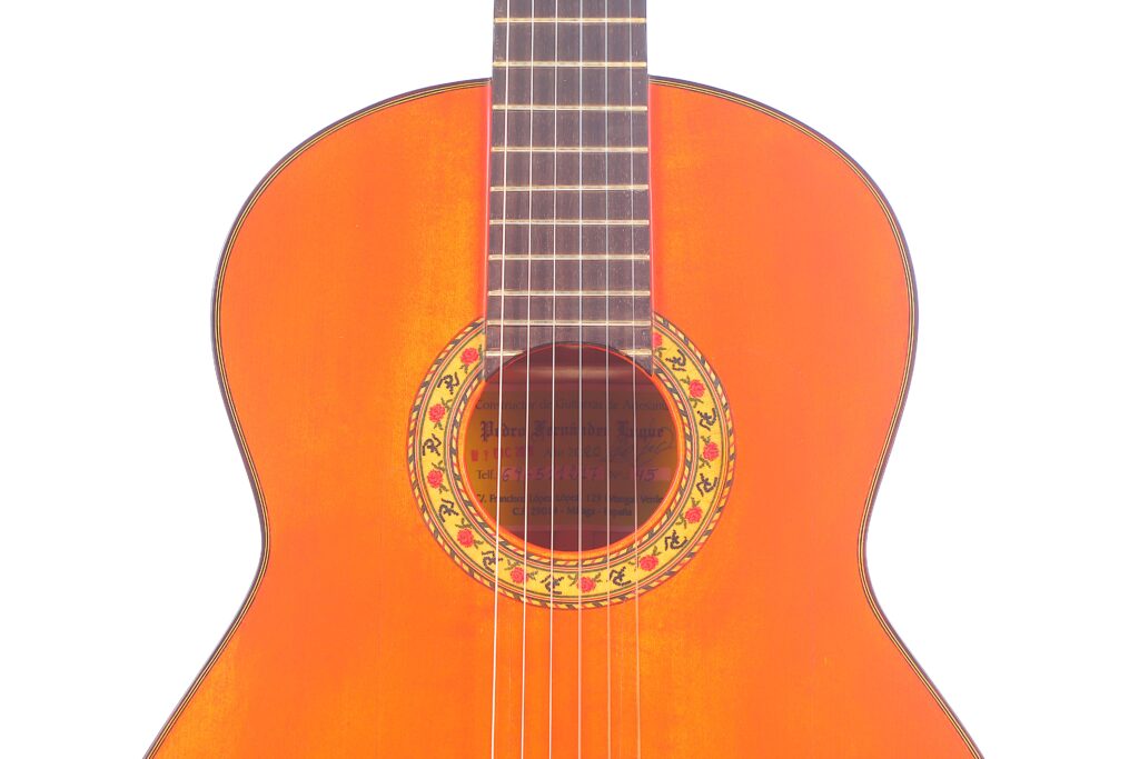 Nahaufnahme Des Oberen Korpus Der Pedro Fernández Luque 2020 Blanca Flamenco-Gitarre Mit Orangefarbener Lackierung, Die Das Schallloch Und Das Griffbrett Vor Einem Weißen Hintergrund Hervorhebt.