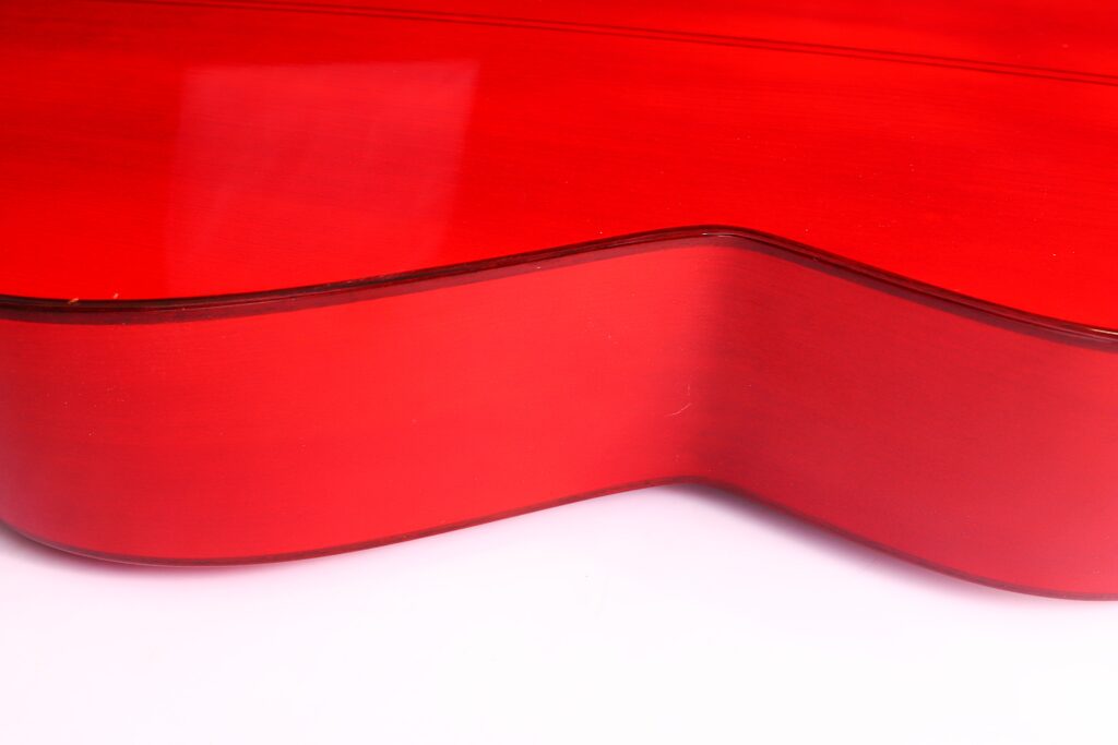 Eine Nahaufnahme Der Leuchtend Roten, Glänzenden Seite Und Der Gebogenen Kante Des Korpus Einer Manuel Guillena 2017 Blanca Flamenco-Gitarre Vor Einem Weißen Hintergrund.