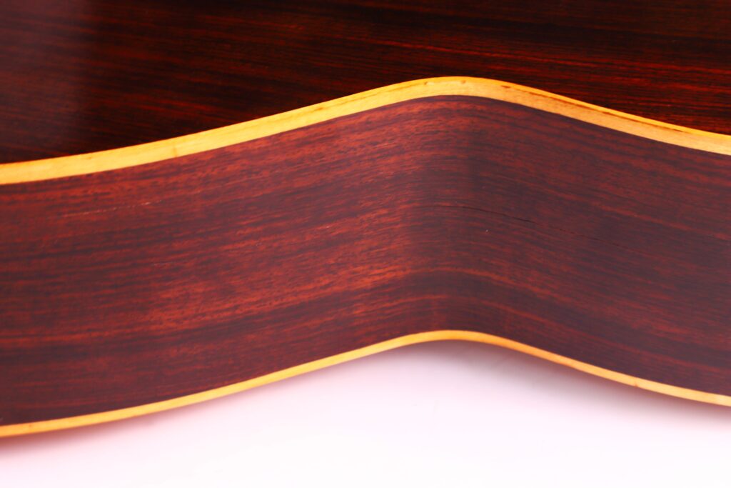 Nahaufnahme Der Gewölbten Seite Einer Vicente Tatay Alabau 1900 Klassische Gitarre, Die Eine Dunkle Holzmaserung Mit Hellen Rändern Vor Einem Weichen Weißen Hintergrund Aufweist.