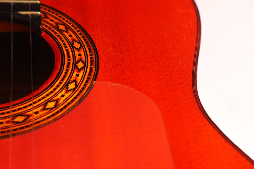 Nahaufnahme Einer Hermanos Conde 1983 Faustino Conde Flamenco-Gitarre Mit Leuchtend Rotem Korpus, Dekorativem Schallloch Und Eleganten Rundungen Vor Weißem Hintergrund.