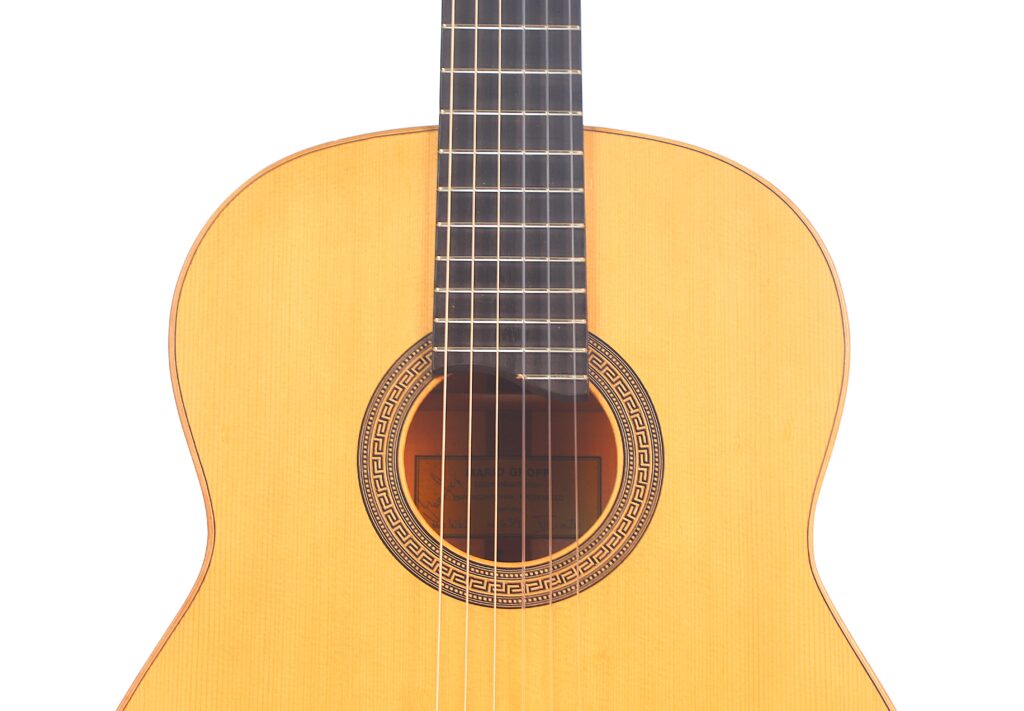 Nahaufnahme Der Mario Gropp 2020 Klassische Gitarre, Die Den Korpus, Den Hals, Die Sechs Saiten, Das Holzfinish Und Die Zierrosette Um Das Schallloch Vor Einem Weißen Hintergrund Zeigt.