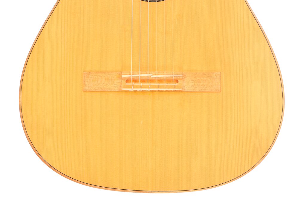 Nahaufnahme Des Korpus Der Mario Gropp 2020 Klassische Gitarre. Hervorzuheben Sind Die Helle Holzoberfläche, Der Steg, Die Saiten Und Das Teilweise Sichtbare Schallloch Am Oberen Rand Des Bildes.