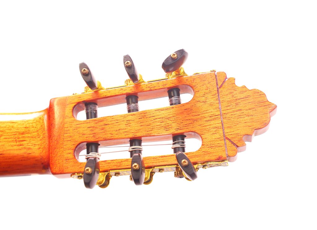 Nahaufnahme Der Kopfplatte Der Pedro Fernández Luque 2020 Blanca Flamenco-Gitarre Mit Holzoberfläche, Schwarzen Stimmwirbeln Und Goldener Hardware Auf Weißem Hintergrund.