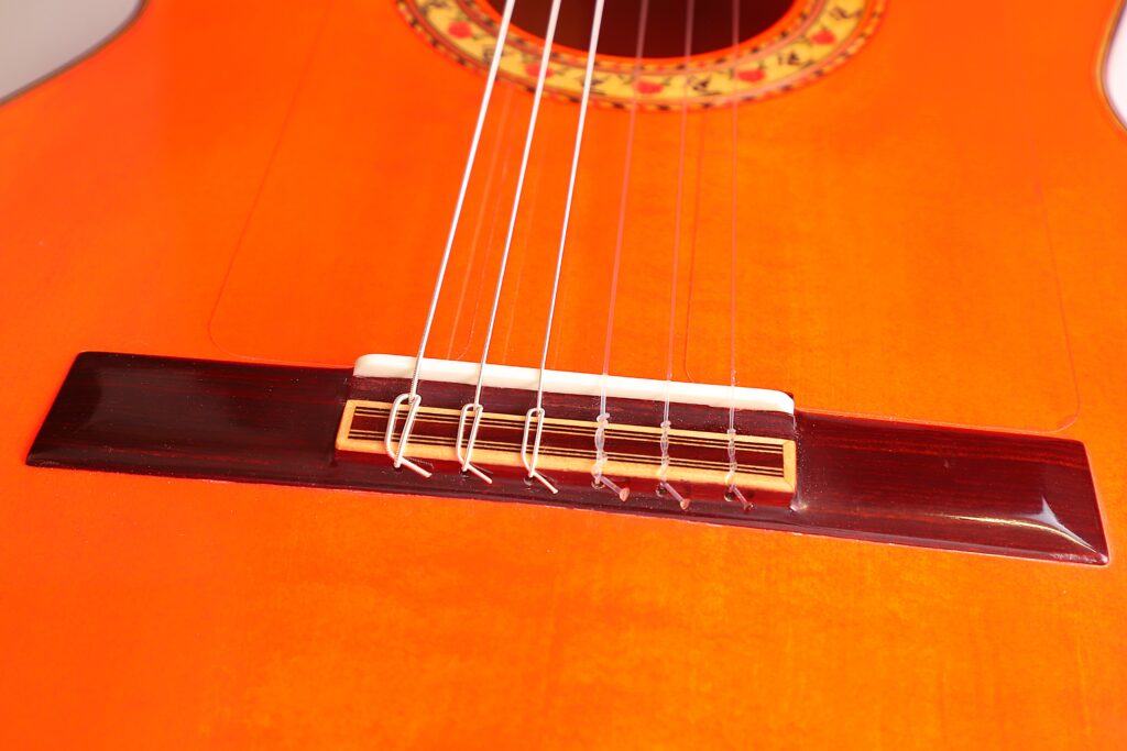 Nahaufnahme Des Stegs Und Der Saiten Einer Pedro Fernández Luque 2020 Blanca Flamenco-Gitarre, Die Die Detaillierte Holzstruktur Und Einen Teil Der Schalllochrosette Hervorhebt.