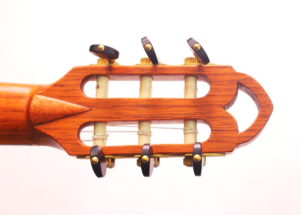 Nahaufnahme Der Kopfplatte Der Mario Gropp 2020 Klassische Gitarre Mit Hölzernen Stimmwirbeln Und Drei Saiten, Mit Warmem Holzton Und Glatter Oberfläche Vor Weißem Hintergrund.