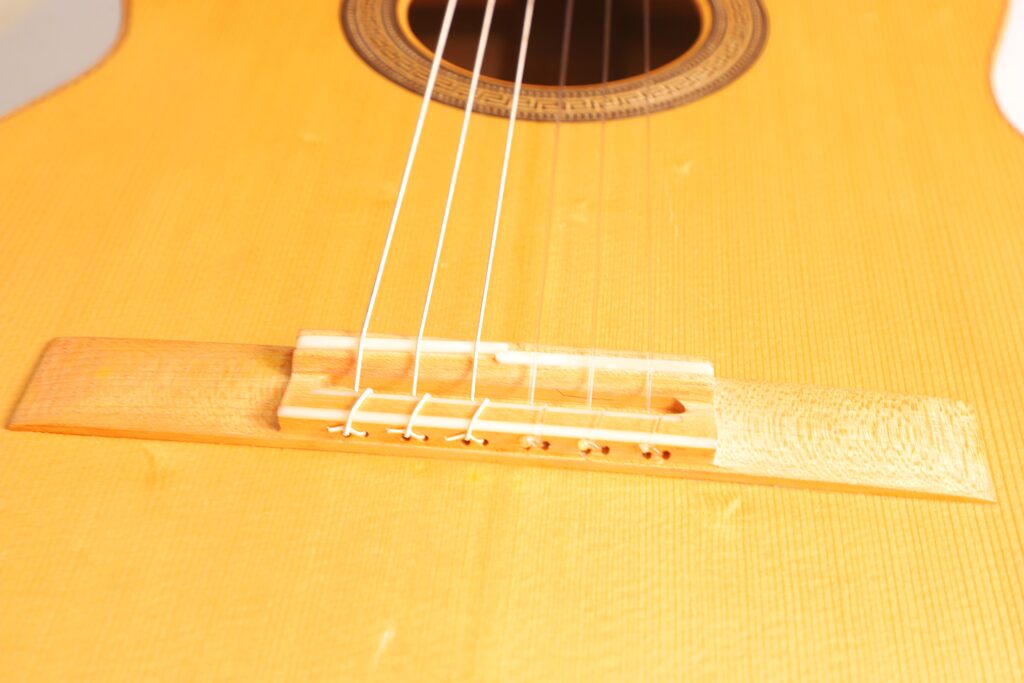 Nahaufnahme Von Steg Und Saiten Der Mario Gropp 2020 Klassische Gitarre, Die Das Detaillierte Schalllochdesign Und Den Edlen Holzkorpus Hervorhebt.