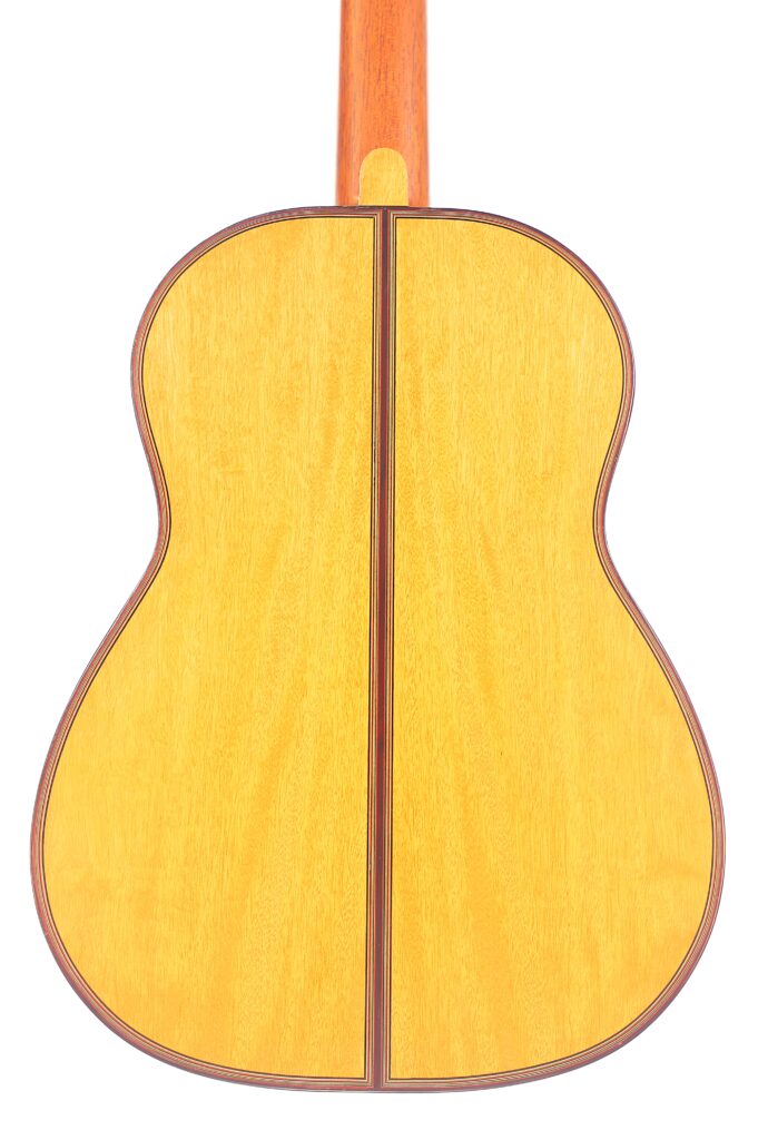 Das Bild Zeigt Die Rückseite Einer Michael Wichmann 2017 Simplicio Klassische Gitarre, Die Eine Helle Holzoberfläche, Einen Zentralen Dunklen Streifen Und Dunkle Zierleisten An Den Rändern Aufweist. Der Gitarrenhals Ist An Der Oberseite Teilweise Sichtbar.