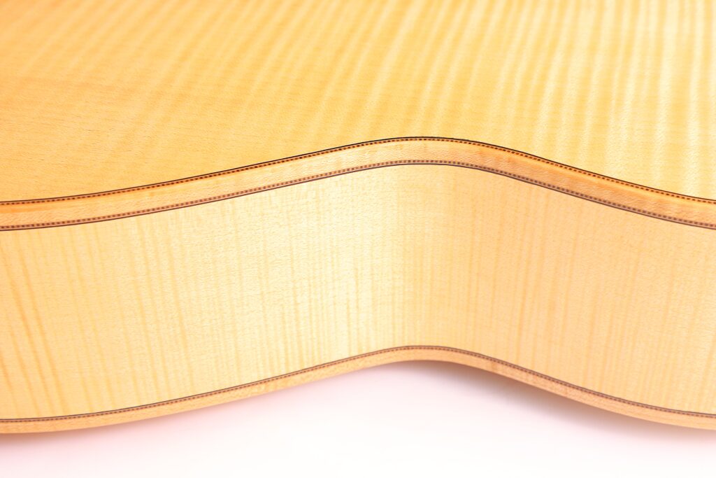 Nahaufnahme Der Seite Und Der Rückseite Der Mario Gropp 2020 Klassische Gitarre. Hervorzuheben Sind Die Helle Holzmaserung, Die Sanften Rundungen Und Die Dekorative Randeinfassung.