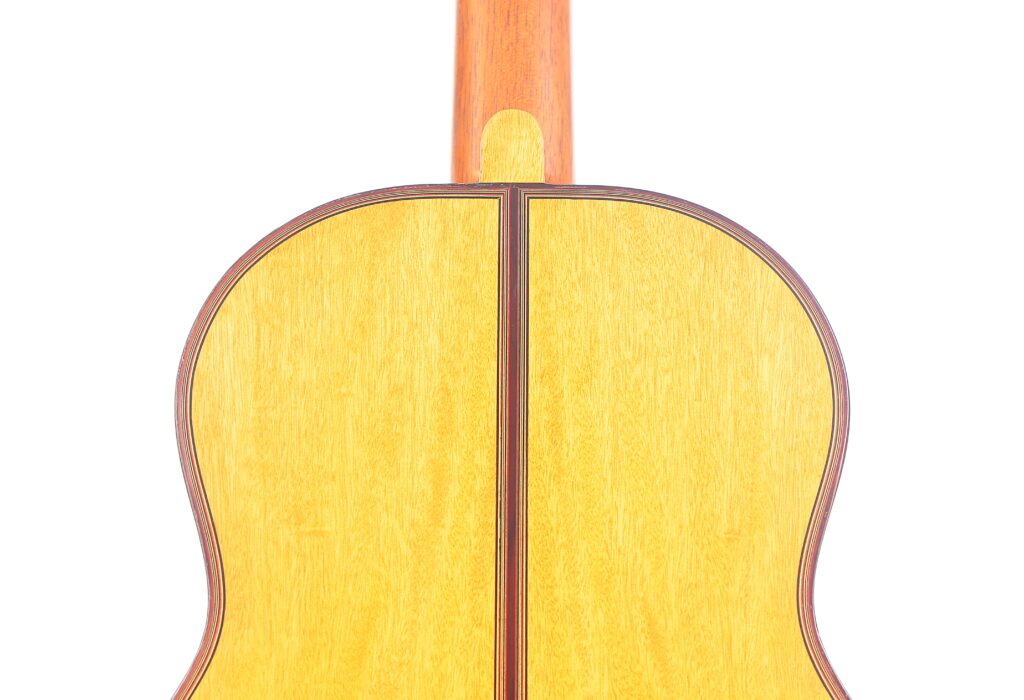 Das Bild Zeigt Die Rückseite Einer Michael Wichmann 2017 Simplicio Klassische Gitarre Mit Einer Hellen Holzoberfläche Und Dunkleren Holzeinfassungen. Der Hals Ragt Vom Korpus Nach Oben Und Steht Vor Einem Schlichten Weißen Hintergrund.