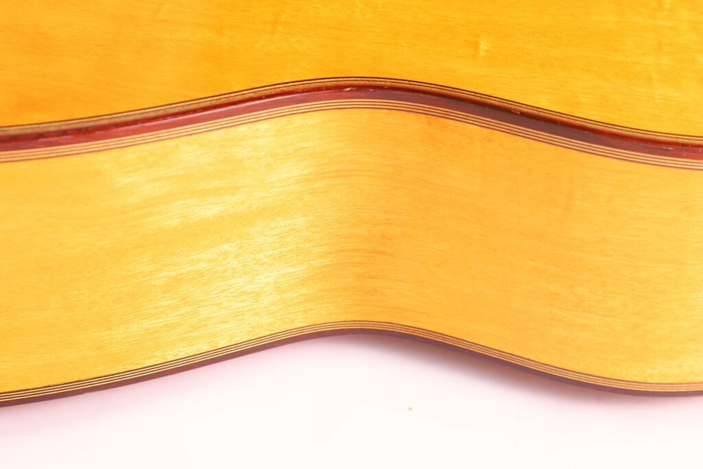 Nahaufnahme Der Michael Wichmann 2017 Simplicio Klassische Gitarre. Hervorzuheben Sind Der Helle Holzkorpus Mit Dunkler Zierleiste Und Die Sanften Kurven Vor Weißem Hintergrund.