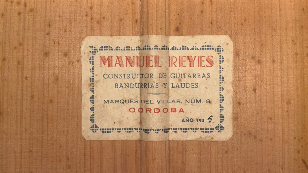 Auf Dem Alten Holzetikett Der Flamenco-Gitarre Von Manuel Reyes Aus Dem Jahr 1955 Steht: &Quot;Manuel Reyes, Constructor De Guitarras, Bandurrias Y Laudes, Marques Del Villar, Núm. 8, Córdoba, Año 195_,&Quot; Mit Blauem Und Rotem Text Innerhalb Eines Gepunkteten Rahmens.
