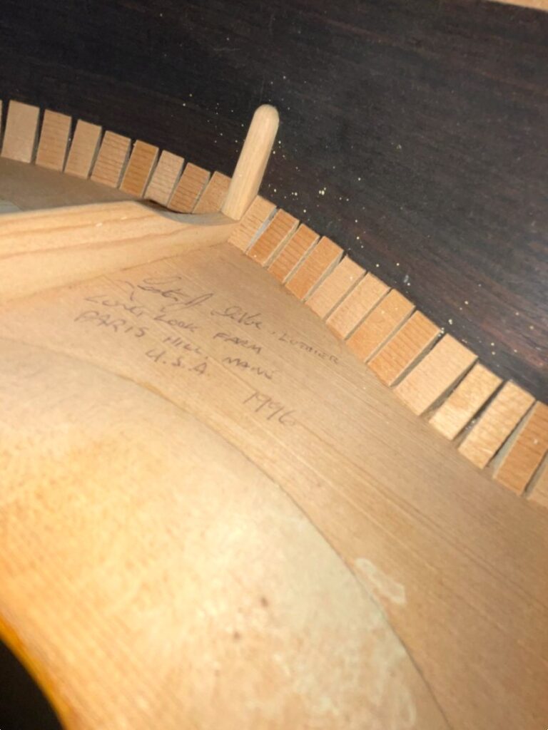Nahaufnahme Der Innenseite Einer Lester Devoe 1996 Negra Flamenco Gitarre, Mit Holzverstrebungen Und Handschriftlichen Notizen Oder Unterschriften Auf Der Beleuchteten Holzinnenseite.
