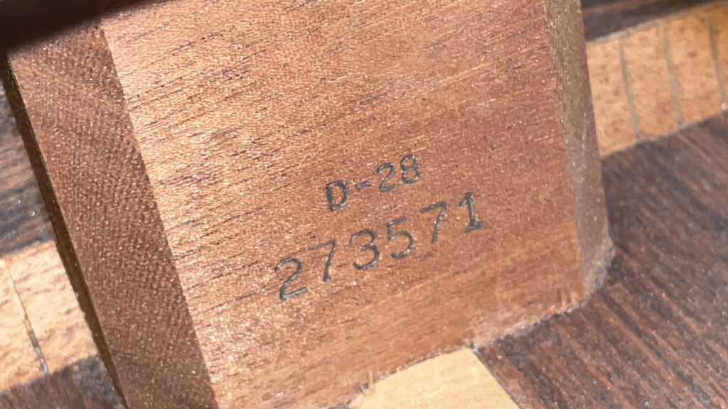 Nahaufnahme Einer Martin D-28 1971 Akustik Gitarre, Die Den Text D-28 Und Die Seriennummer 273571 In Schwarzer Tinte Auf Der Holzoberfläche Mit Sichtbarer Maserung Und Eckverbindungen Zeigt.