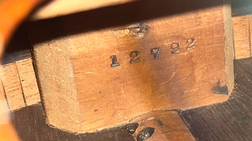 Nahaufnahme Der Naturbraunen Holzmaserung Einer Martin 0-30 1917 Akustik Gitarre, Mit Der In Schwarzer Tinte Gestempelten Nummer 12992, Mit Dunklen Flecken Und Einer Sichtbaren Naht Auf Der Holzoberfläche.