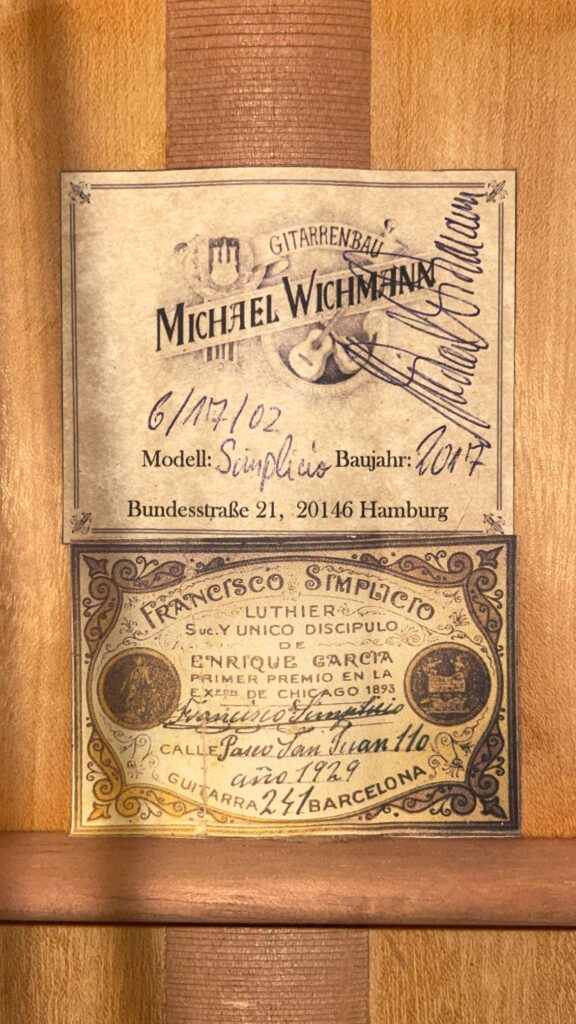 Im Inneren Des Holzinstruments Befindet Sich Ein Etikett Mit Der Aufschrift &Quot;Michael Wichmann 2017 Simplicio Klassische Gitarre, Hamburg&Quot;, Darüber Ein Etikett Im Vintage-Stil Für &Quot;Francesco Simplicio, Luthier, Barcelona&Quot;.