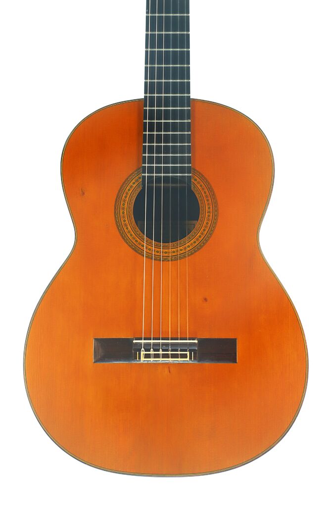 Eine klassische Gitarre von Ignacio Fleta aus dem Jahr 1992 – eine klassische Akustikgitarre mit einem Korpus aus Holz, sechs Saiten und einer verzierten Rosette, die das Schallloch umgibt – ist vor einem weißen Hintergrund fotografiert. Eine klassische Gitarre von Ignacio Fleta aus dem Jahr 1992 – eine klassische Akustikgitarre mit einem Korpus aus Holz, sechs Saiten und einer verzierten Rosette, die das Schallloch umgibt – ist vor einem weißen Hintergrund fotografiert.