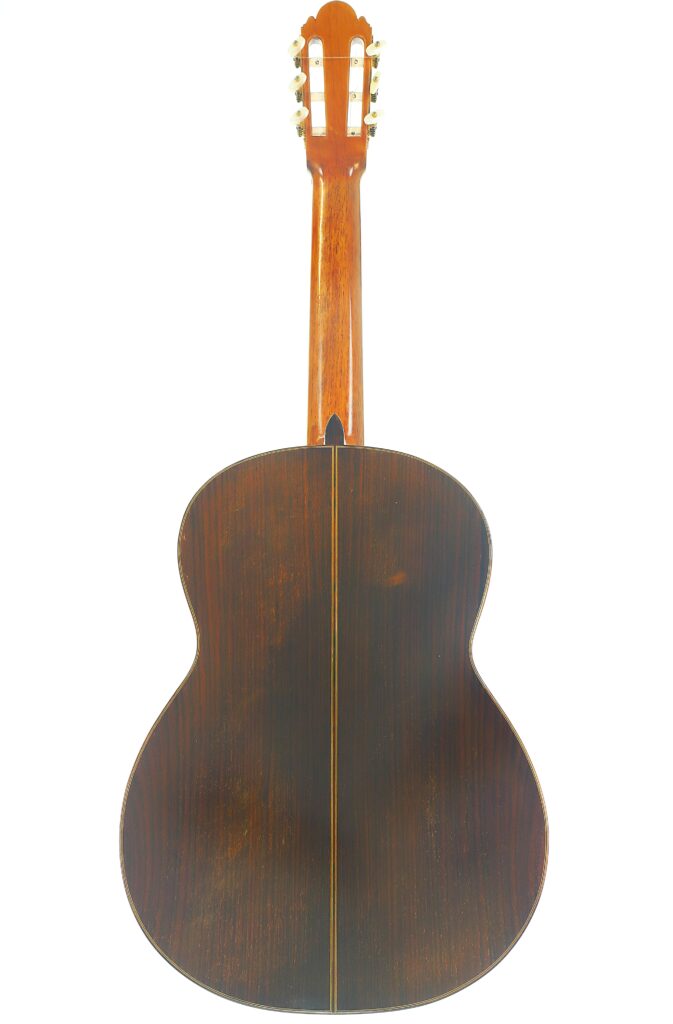 Die Rückseite der „Ignacio Fleta 1992 Klassische Gitarre“ besticht durch einen Korpus aus dunklem Holz, der durch eine kontrastierende, hellere Mittelnaht hervorgehoben wird, sowie durch einen tiefbraunen Hals und edle goldene Stimmwirbel. Die Rückseite der „Ignacio Fleta 1992 Klassische Gitarre“ besticht durch einen Korpus aus dunklem Holz, der durch eine kontrastierende, hellere Mittelnaht hervorgehoben wird, sowie durch einen tiefbraunen Hals und edle goldene Stimmwirbel.