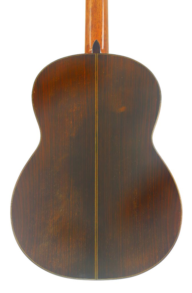 Der Boden der „Ignacio Fleta 1992 Klassische Gitarre“ besteht aus dunklem Holz, das durch einen vertikalen hellen Streifen in der Mitte akzentuiert wird; oben ist ein Teil des Gitarrenhalses zu sehen. Der Boden der „Ignacio Fleta 1992 Klassische Gitarre“ besteht aus dunklem Holz, das durch einen vertikalen hellen Streifen in der Mitte akzentuiert wird; oben ist ein Teil des Gitarrenhalses zu sehen.