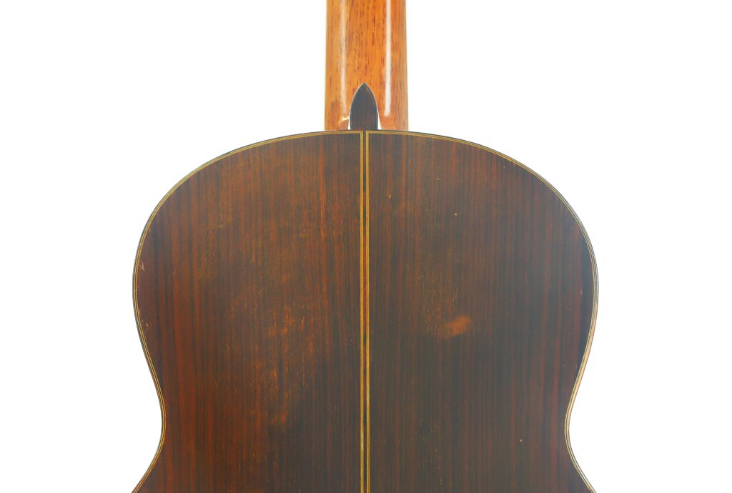 Rückansicht der „Ignacio Fleta 1992 Klassische Gitarre“ mit dunkler Holzoberfläche, einer mittigen Trennlinie und dezenten Maserungsmustern, die die raffinierte Handwerkskunst unterstreichen. Rückansicht der „Ignacio Fleta 1992 Klassische Gitarre“ mit dunkler Holzoberfläche, einer mittigen Trennlinie und dezenten Maserungsmustern, die die raffinierte Handwerkskunst unterstreichen.