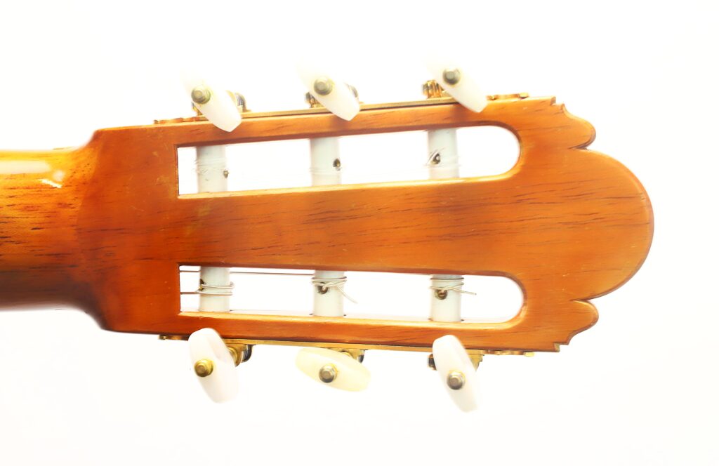 Nahaufnahme des Kopfstücks der „Ignacio Fleta 1992 Klassische Gitarre“ mit weißen Stimmwirbeln und einer hellen Holzmaserung vor einem schlichten weißen Hintergrund. Nahaufnahme des Kopfstücks der „Ignacio Fleta 1992 Klassische Gitarre“ mit weißen Stimmwirbeln und einer hellen Holzmaserung vor einem schlichten weißen Hintergrund.