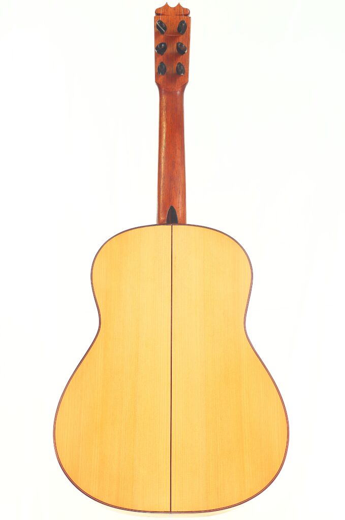Das Bild zeigt die Rückseite einer „Hermanos Conde 1988 Faustino Conde Flamenco-Gitarre“ mit naturbelassener Holzoberfläche, Mittelnaht und rotbraunem Hals vor weißem Hintergrund. Das Bild zeigt die Rückseite einer „Hermanos Conde 1988 Faustino Conde Flamenco-Gitarre“ mit naturbelassener Holzoberfläche, Mittelnaht und rotbraunem Hals vor weißem Hintergrund.