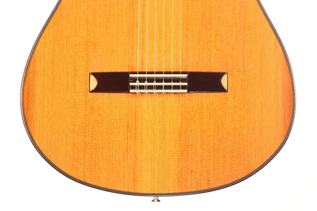 Nahaufnahme des Korpus der Antonio Morales Nogués 2020 Negra Flamenco-Gitarre mit sechs Saiten, einem Holzsteg, einer warmen, natürlichen Lackierung und mit einem dünnen dunklen Rand versehenen Kanten. Nahaufnahme des Korpus der Antonio Morales Nogués 2020 Negra Flamenco-Gitarre mit sechs Saiten, einem Holzsteg, einer warmen, natürlichen Lackierung und mit einem dünnen dunklen Rand versehenen Kanten.