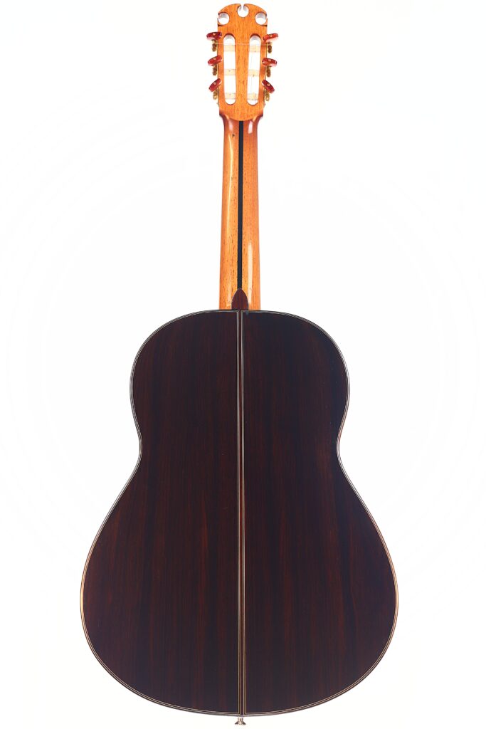 Die Antonio Morales Nogués 2020 Negra Flamenco-Gitarre ist von hinten abgebildet, mit einem Korpus aus dunklem Holz mit einer zentralen Naht und einem Hals und einer Kopfplatte aus hellem Holz, fotografiert auf einem weißen Hintergrund. Die Antonio Morales Nogués 2020 Negra Flamenco-Gitarre ist von hinten abgebildet, mit einem Korpus aus dunklem Holz mit einer zentralen Naht und einem Hals und einer Kopfplatte aus hellem Holz, fotografiert auf einem weißen Hintergrund.