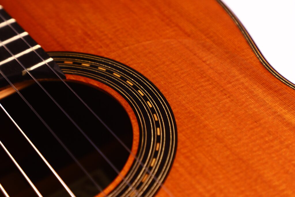 Nahaufnahme der Antonio Morales Nogués 2020 Negra Flamenco-Gitarre, die das Schallloch, die Saiten und die detaillierte Holzverarbeitung am Rand hervorhebt. Das Bild zeigt die feine Textur und die fachmännische Konstruktion der Gitarre. Nahaufnahme der Antonio Morales Nogués 2020 Negra Flamenco-Gitarre, die das Schallloch, die Saiten und die detaillierte Holzverarbeitung am Rand hervorhebt. Das Bild zeigt die feine Textur und die fachmännische Konstruktion der Gitarre.