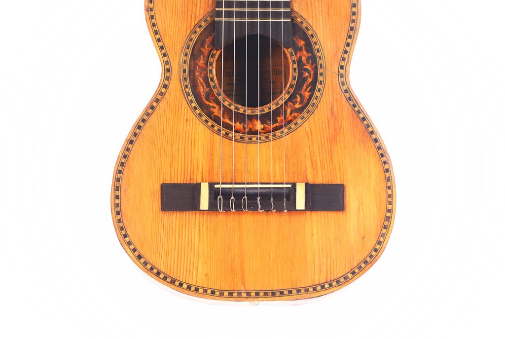 Nahaufnahme des Korpus der Vicente Carillo 1925 Terz Gitarre mit dekorativer Einlage um das Schallloch und die Ränder, vor weißem Hintergrund. Nahaufnahme des Korpus der Vicente Carillo 1925 Terz Gitarre mit dekorativer Einlage um das Schallloch und die Ränder, vor weißem Hintergrund.