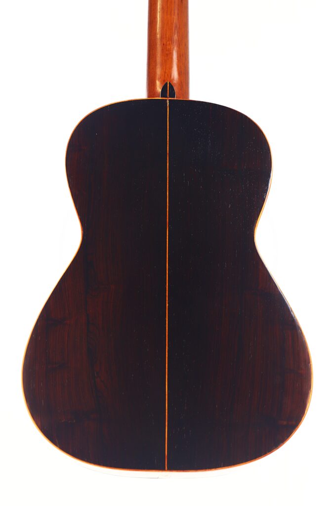 Die Franciso Pau 1890 Klassische Gitarre wird von hinten gezeigt, mit dunkler Holzoberfläche, einer zentralen Naht und hellen Zierleisten entlang des Korpus, fotografiert auf einem schlichten weißen Hintergrund. Die Franciso Pau 1890 Klassische Gitarre wird von hinten gezeigt, mit dunkler Holzoberfläche, einer zentralen Naht und hellen Zierleisten entlang des Korpus, fotografiert auf einem schlichten weißen Hintergrund.