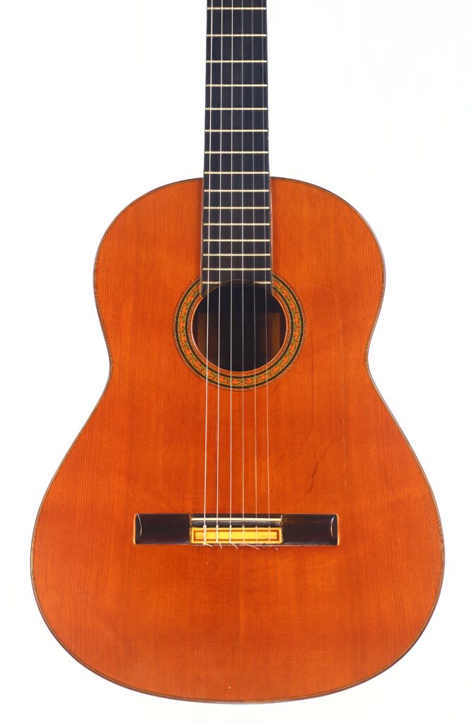 Die Hermanos Conde 1971 Faustino Conde Negra Flamenco-Gitarre hat einen Holzkorpus, sechs Saiten, ein dunkles Griffbrett und eine aufwendige Rosette um das Schallloch, die auf weißem Hintergrund zu sehen ist. Die Hermanos Conde 1971 Faustino Conde Negra Flamenco-Gitarre hat einen Holzkorpus, sechs Saiten, ein dunkles Griffbrett und eine aufwendige Rosette um das Schallloch, die auf weißem Hintergrund zu sehen ist.