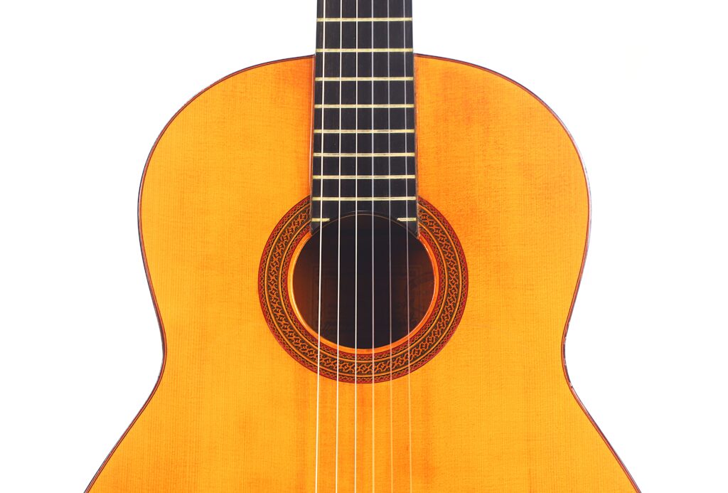 Nahaufnahme des Korpus und der Saiten einer Flamenco-Gitarre von Marcelino López Nieto aus dem Jahr 1959 vor einem weißen Hintergrund. Nahaufnahme des Korpus und der Saiten einer Flamenco-Gitarre von Marcelino López Nieto aus dem Jahr 1959 vor einem weißen Hintergrund.