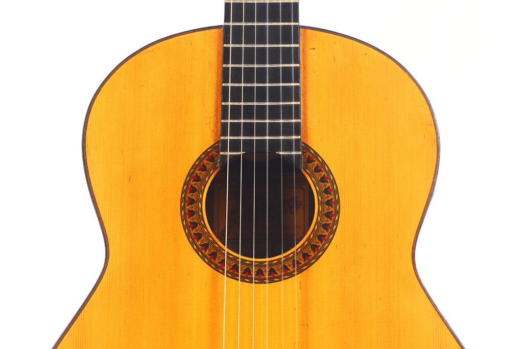 Nahaufnahme der Jose Ramirez 1a 1959 PB Klassische Gitarre. Hervorzuheben sind die dekorative Rosette, die sechs Saiten und die glänzende Holzoberfläche vor einem weißen Hintergrund. Nahaufnahme der Jose Ramirez 1a 1959 PB Klassische Gitarre. Hervorzuheben sind die dekorative Rosette, die sechs Saiten und die glänzende Holzoberfläche vor einem weißen Hintergrund.