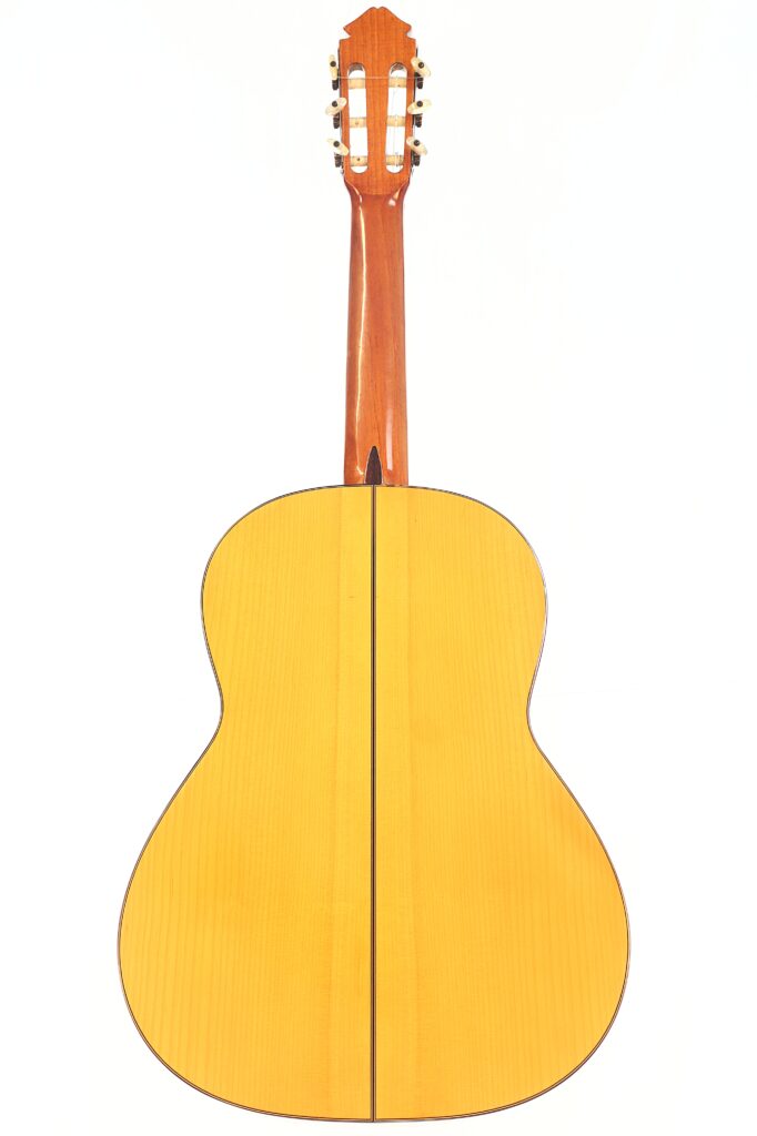 Die Rückansicht der Marcelino López Nieto 1959 Flamenco Gitarre zeichnet sich durch eine helle Holzoberfläche, einen gewölbten Korpus, eine vertikale Mittelnaht und einen Hals mit Stimmwirbeln an der Oberseite aus. Die Rückansicht der Marcelino López Nieto 1959 Flamenco Gitarre zeichnet sich durch eine helle Holzoberfläche, einen gewölbten Korpus, eine vertikale Mittelnaht und einen Hals mit Stimmwirbeln an der Oberseite aus.