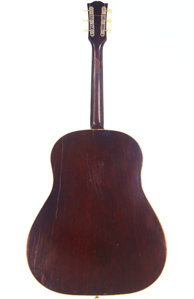 Das Bild zeigt die Rückansicht einer Gibson J-45 1954 Akustische Gitarre mit dunklem Holzfinish, sichtbaren Kratzern und Gebrauchsspuren am Korpus; die Kopfplatte und die Stimmwirbel sind ebenfalls abgebildet. Das Bild zeigt die Rückansicht einer Gibson J-45 1954 Akustische Gitarre mit dunklem Holzfinish, sichtbaren Kratzern und Gebrauchsspuren am Korpus; die Kopfplatte und die Stimmwirbel sind ebenfalls abgebildet.