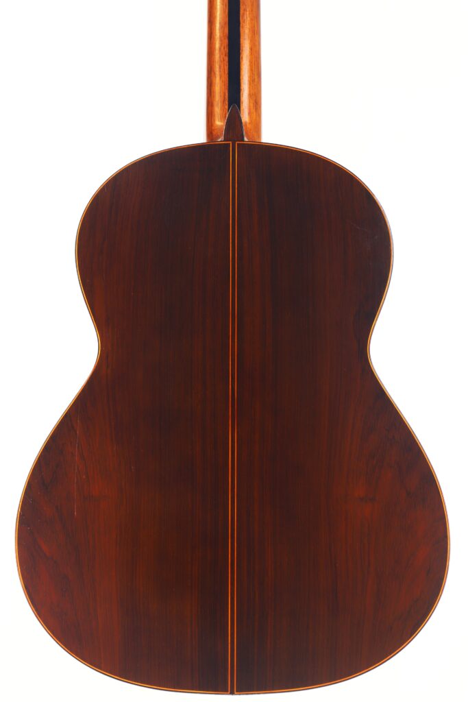 Das Bild zeigt die Rückseite einer Jose Ramirez 1a 1959 PB Klassische Gitarre, gefertigt aus dunklem, poliertem Holz mit einer zentralen Naht und subtilen Holzmaserungen, vor einem schlichten weißen Hintergrund. Das Bild zeigt die Rückseite einer Jose Ramirez 1a 1959 PB Klassische Gitarre, gefertigt aus dunklem, poliertem Holz mit einer zentralen Naht und subtilen Holzmaserungen, vor einem schlichten weißen Hintergrund.