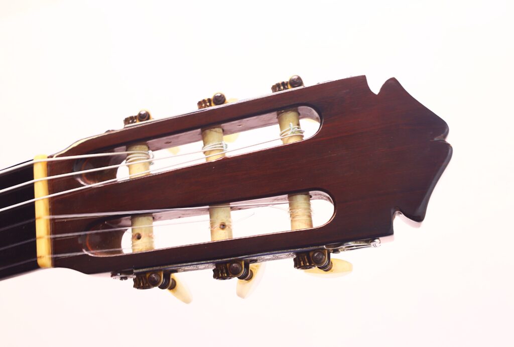 Nahaufnahme der Kopfplatte einer Flamenco-Gitarre von Marcelino López Nieto aus dem Jahr 1959. Hervorzuheben sind Stimmwirbel, Saiten und Holzdetails vor einem schlichten weißen Hintergrund. Nahaufnahme der Kopfplatte einer Flamenco-Gitarre von Marcelino López Nieto aus dem Jahr 1959. Hervorzuheben sind Stimmwirbel, Saiten und Holzdetails vor einem schlichten weißen Hintergrund.