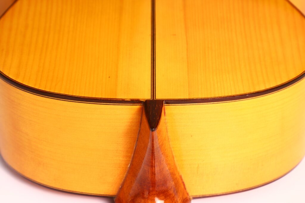 Nahaufnahme des Bodens und der Zargen der Marcelino López Nieto 1959 Flamenco-Gitarre, wobei die Stelle hervorgehoben wird, an der der Hals auf den Korpus trifft. Das Holz weist eine glänzende, hellbraune Oberfläche mit kontrastierenden dunkleren Akzenten auf. Nahaufnahme des Bodens und der Zargen der Marcelino López Nieto 1959 Flamenco-Gitarre, wobei die Stelle hervorgehoben wird, an der der Hals auf den Korpus trifft. Das Holz weist eine glänzende, hellbraune Oberfläche mit kontrastierenden dunkleren Akzenten auf.