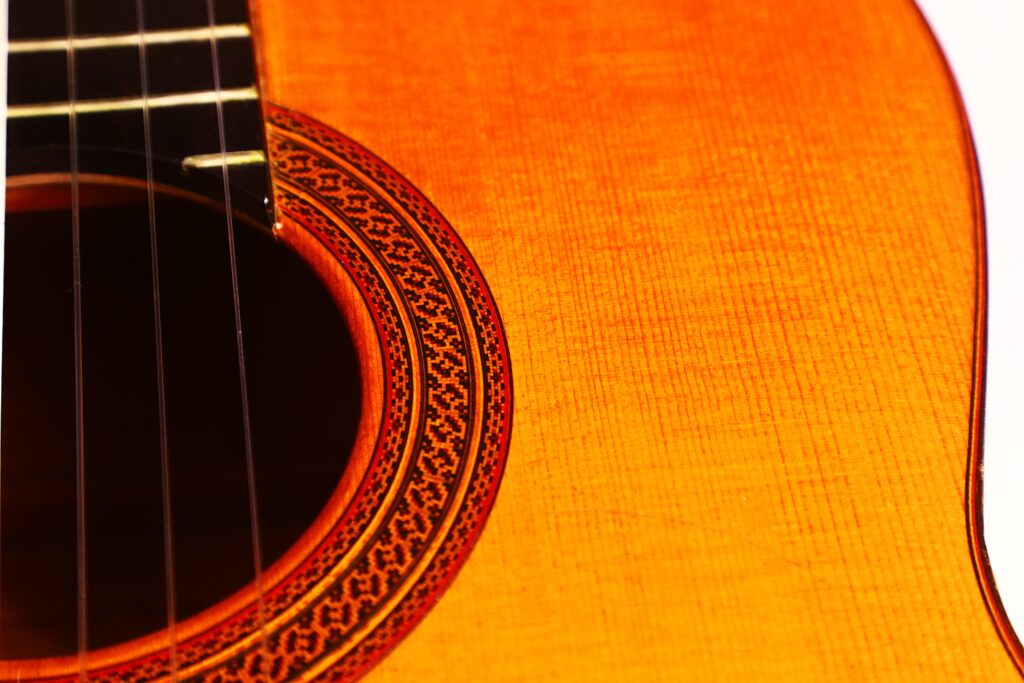Nahaufnahme einer Flamenco-Gitarre von Marcelino López Nieto aus dem Jahr 1959. Hervorzuheben sind das Schallloch, detaillierte Rosettenmuster und ein Teil der Saiten auf einer warmen Holzoberfläche. Nahaufnahme einer Flamenco-Gitarre von Marcelino López Nieto aus dem Jahr 1959. Hervorzuheben sind das Schallloch, detaillierte Rosettenmuster und ein Teil der Saiten auf einer warmen Holzoberfläche.