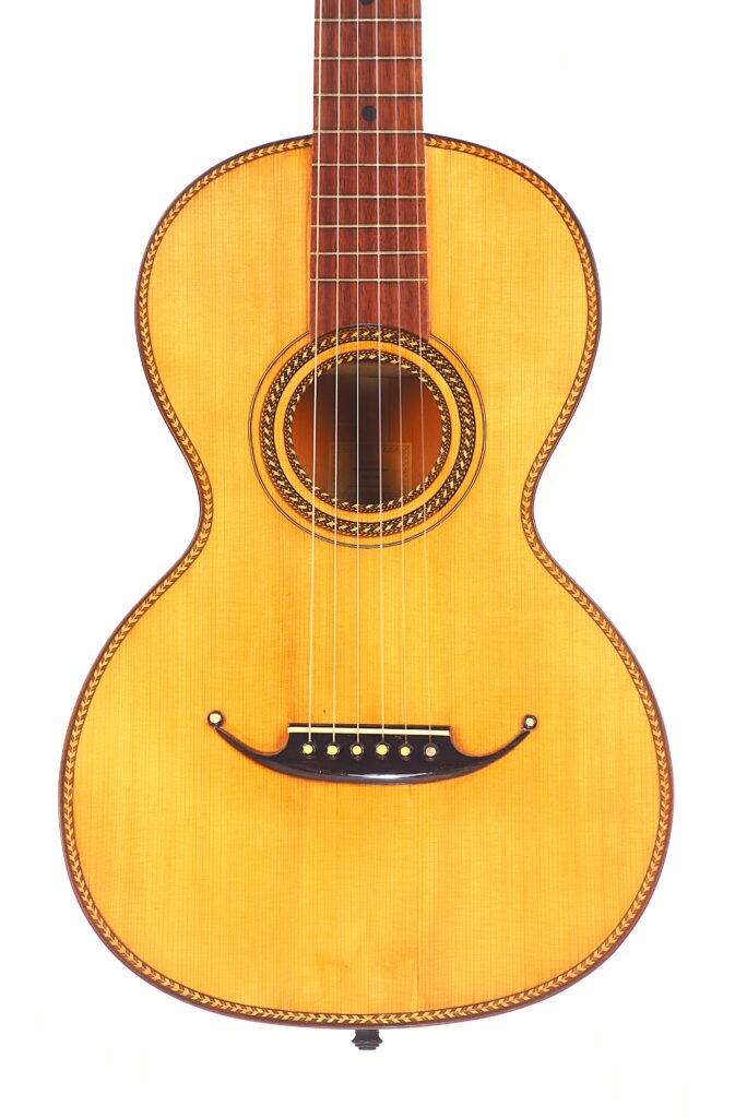 Die Marc Antonio Romantikgitarre ist eine klassische Akustikgitarre mit leichtem Holzkorpus, sechs Saiten und dekorativen Einlagen um das Schallloch und an den Rändern, die auf weißem Hintergrund abgebildet sind. Die Marc Antonio Romantikgitarre ist eine klassische Akustikgitarre mit leichtem Holzkorpus, sechs Saiten und dekorativen Einlagen um das Schallloch und an den Rändern, die auf weißem Hintergrund abgebildet sind.